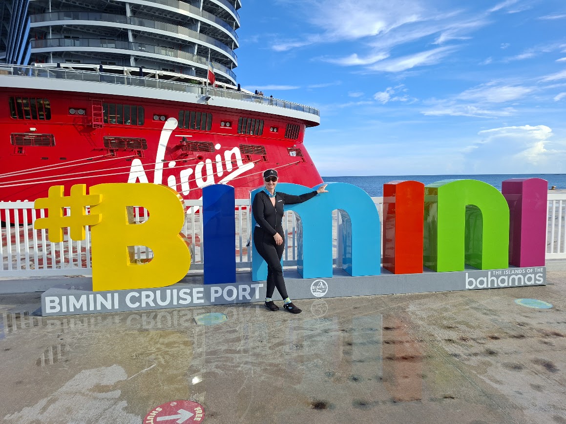 Judy in Bimini with Virgin Voyages Resilient Lady behind her